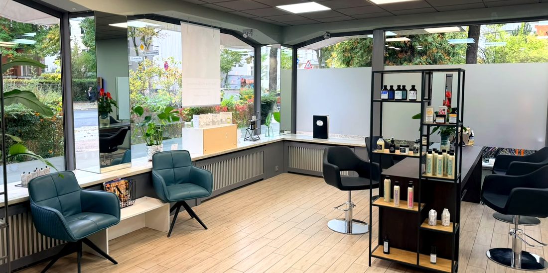 Heller Wartebereich mit grünen Sesseln und großen Fenstern im Salon Success Hairdress